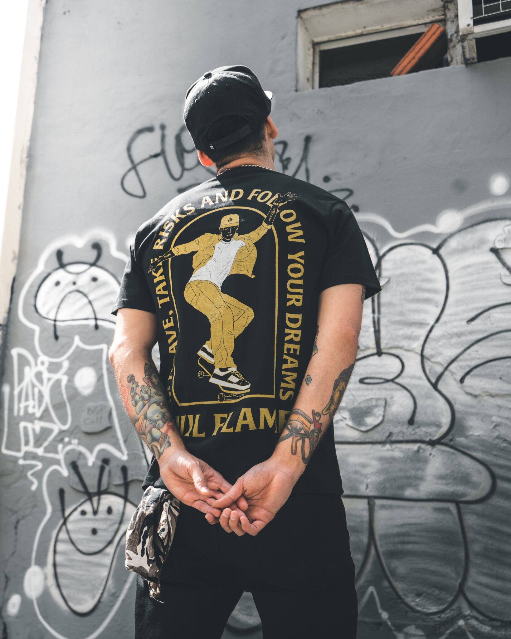 guy wearing a black graphic tshirt looking at graffiti